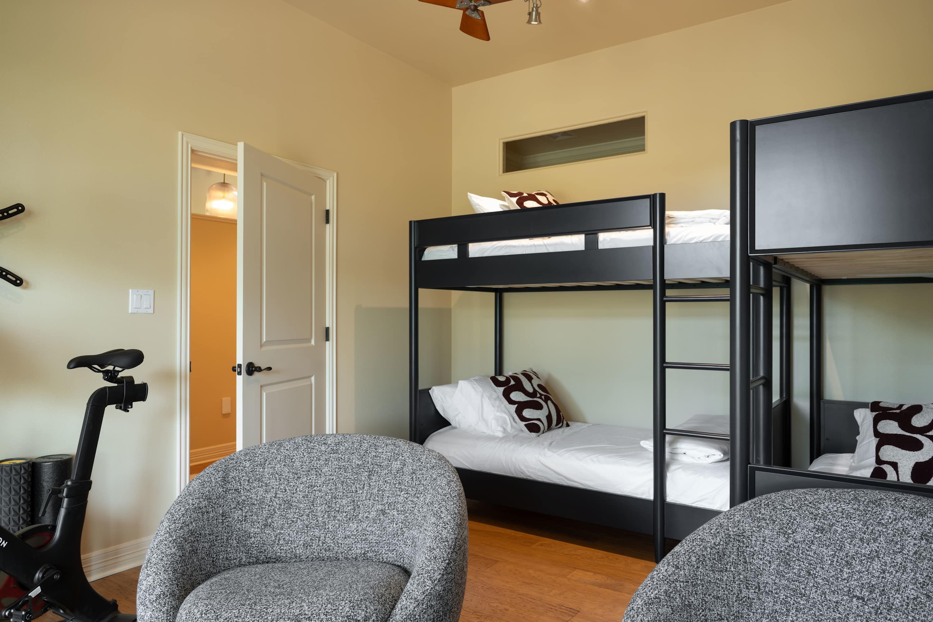 A bunk bed room with a bicycle, a door, and a small window.