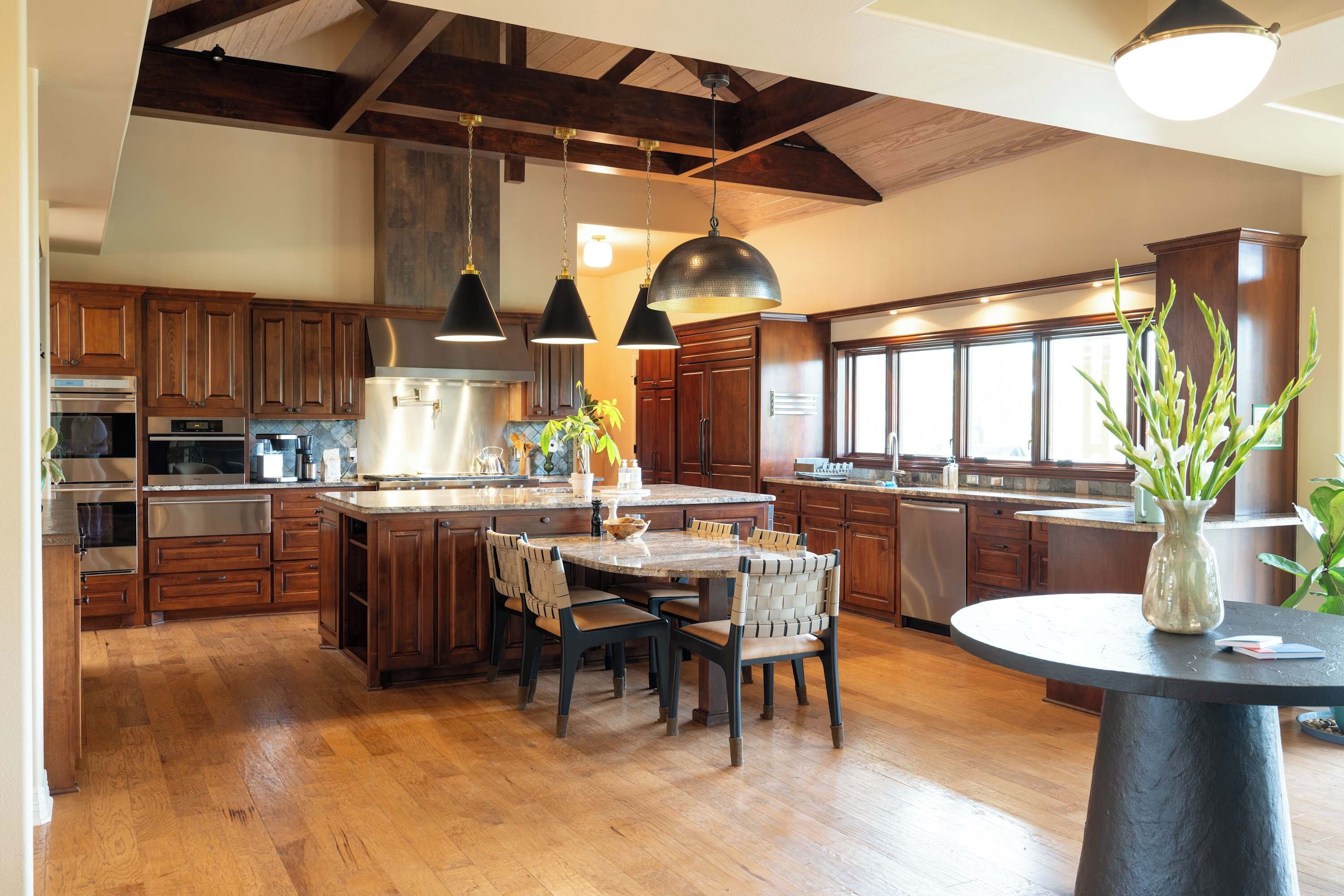 A modern kitchen with wooden cabinets, stainless steel appliances, and a central island with seating.