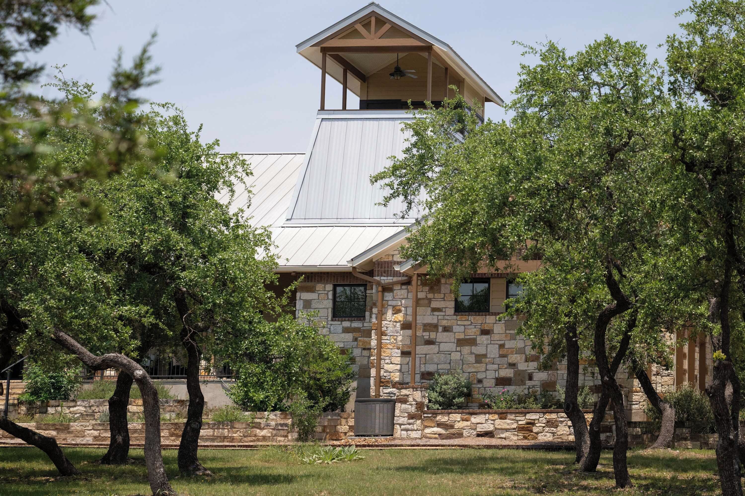 A stone building with a metal roof, surrounded by trees.