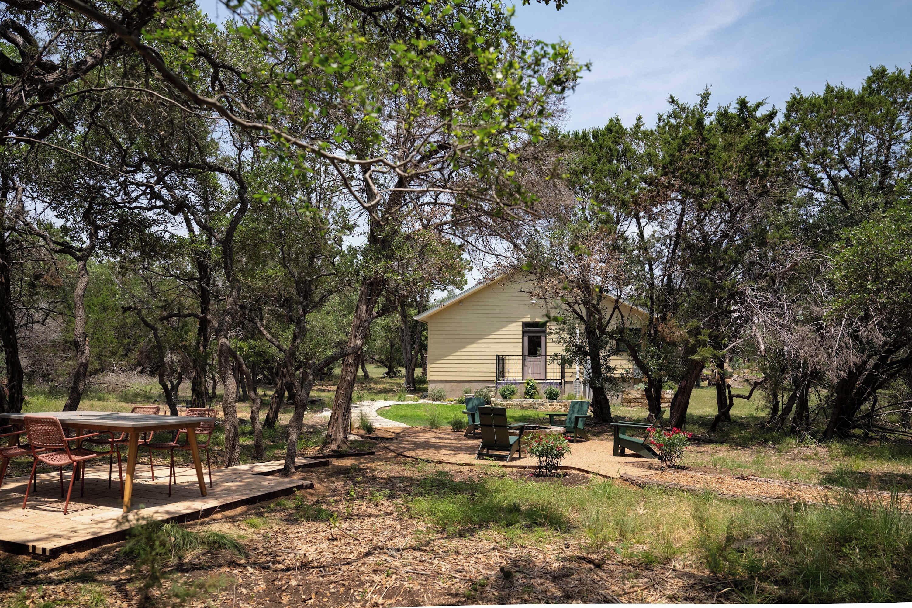 A house surrounded by trees with a patio area and outdoor seating.