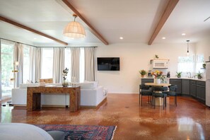 Una sala de estar moderna con un sofá, una mesa de centro de madera y un televisor montado en la pared.