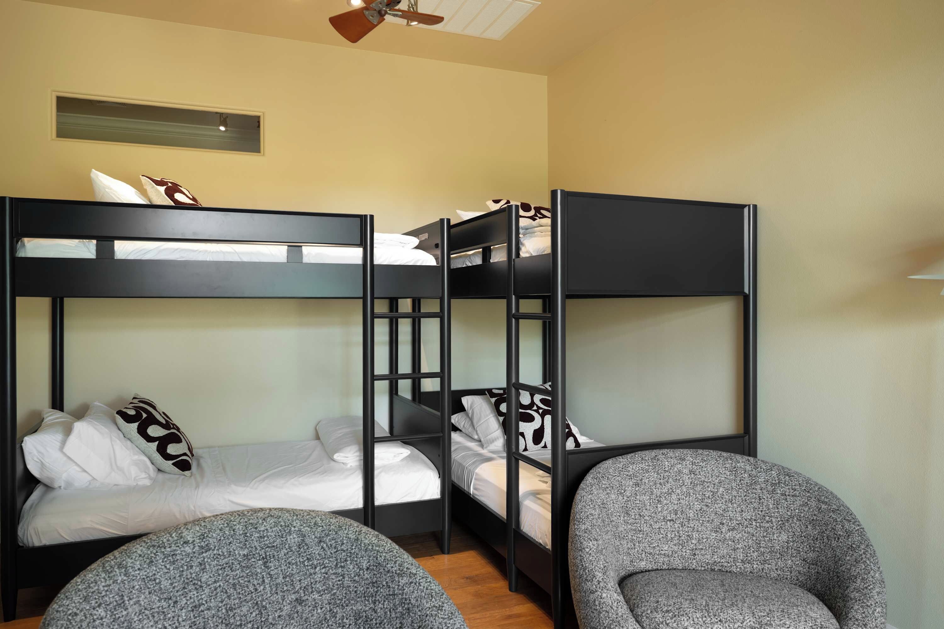 A bunk bed room with a ceiling fan, a window, and a small table.