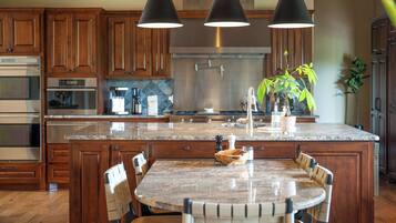 A kitchen with wooden cabinets, stainless steel appliances, a granite countertop, and a dining area with a table and chairs.