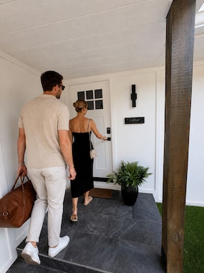 Ein Mann und eine Frau gehen auf eine Tür zu, an der ein Schild mit der Aufschrift 'Velvel' hängt.