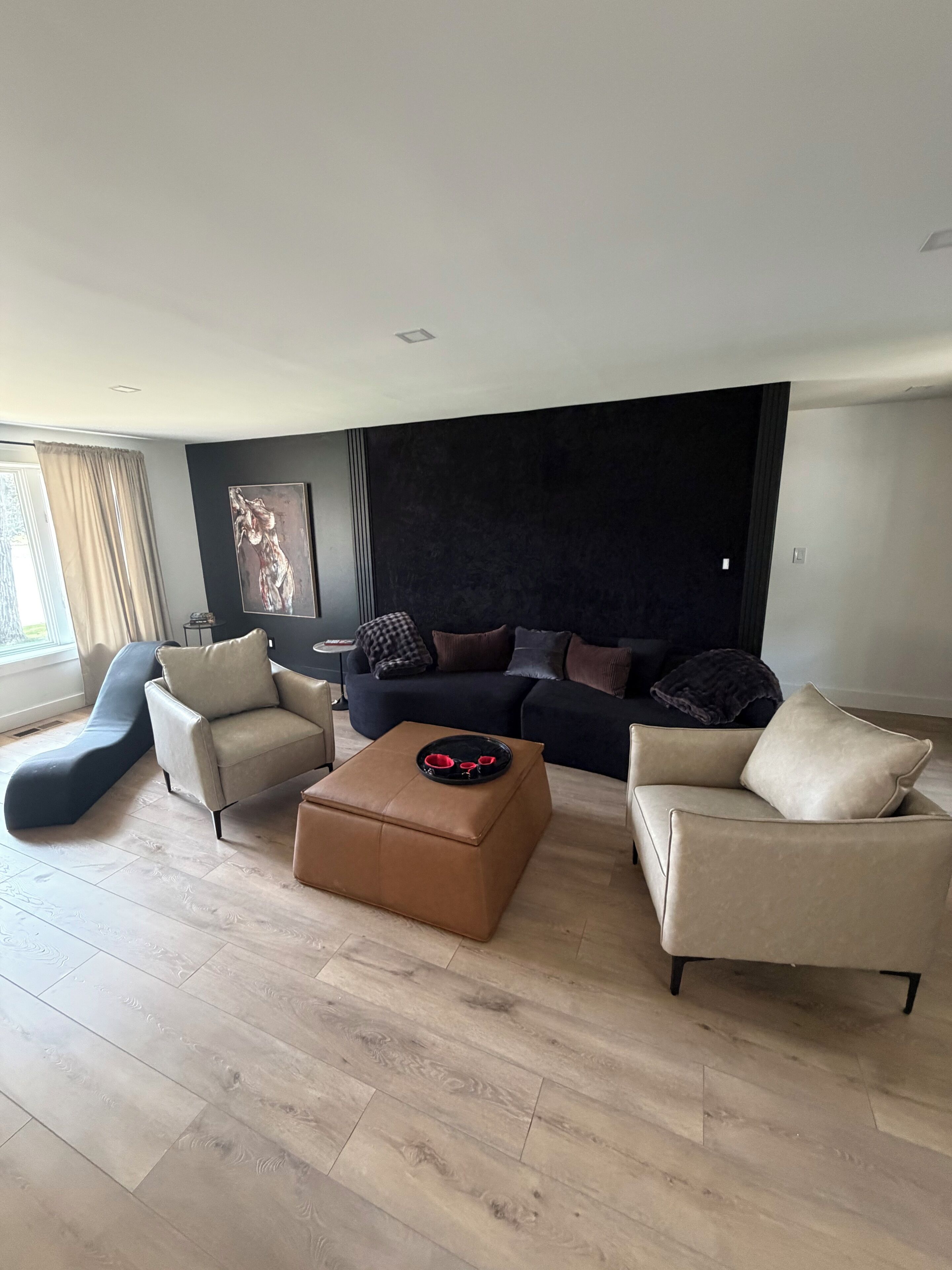 Una sala de estar moderna con un sofá, dos sillones, una mesita de centro y un sillón reclinable azul único.