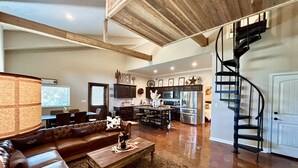 A spacious living area with a leather sofa, a coffee table, and a kitchen in the background. - The Vine (New Ulm)