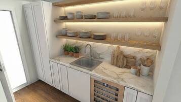 A kitchen with white cabinetry, a marble countertop, a built-in sink, and shelves with plates and glasses.