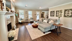 A spacious living room with a fireplace, a large grey sectional sofa, two armchairs, a coffee table, and a decorative vase. - The Vine (New Ulm)