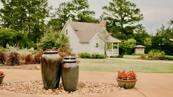 Une maison dotée d’un jardin bien entretenu, agrémenté de deux grands vases et d’une plante en pot.