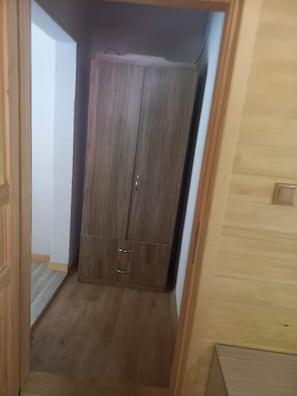 A narrow hallway with a wooden wardrobe and a door on the left.