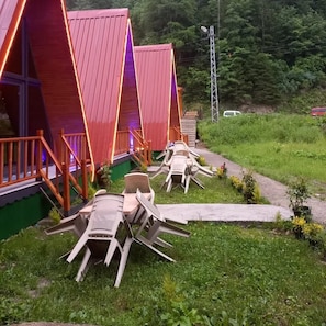 A row of triangular-roofed cabins with outdoor seating areas.