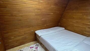 Pequeña habitación con cama individual, paneles de madera en las paredes y una alfombra estampada en el suelo.