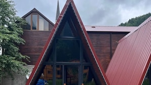 En bygning med en trekantet form, træfacade og en glasdør.