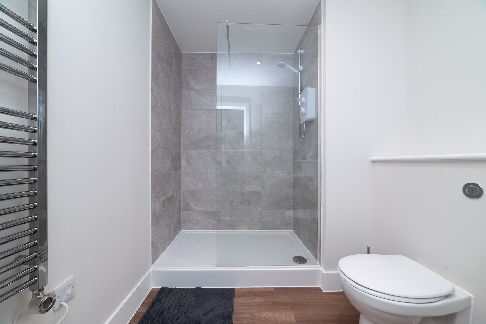 Une salle de bain moderne avec une douche à parois de verre, des toilettes blanches et un porte-serviettes.