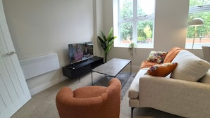 A living room with a sofa, a coffee table, a television, and a potted plant. - Central 1BR Apartment in Hull’s Historic Old Town (Kingston upon Hull)