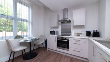 A modern kitchen with white cabinetry, a built-in oven, a microwave, and a stainless steel range hood.