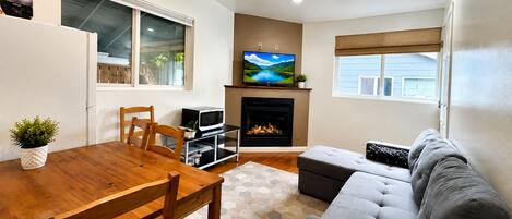 A modern living room with a fireplace, a television, and a dining area with a wooden table and chairs.