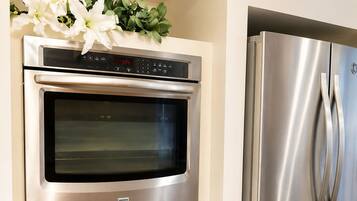 A kitchen with a built-in oven and a stainless steel refrigerator.
