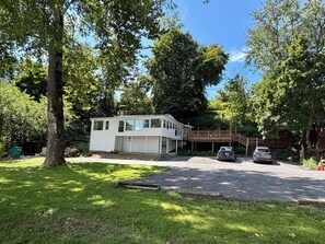 Een herenhuis met garage, omgeven door bomen en een verharde oprit.