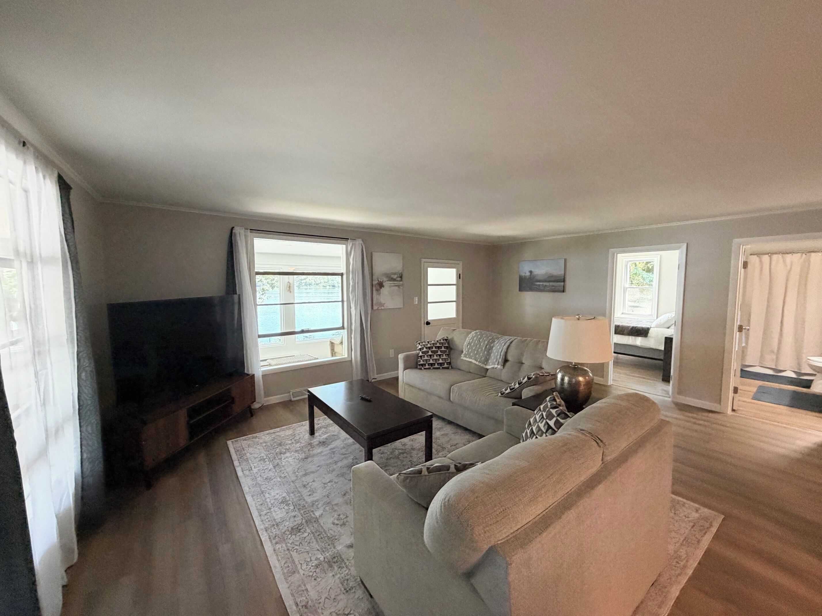 A living room with a sofa, a coffee table, a TV, and a window with curtains.