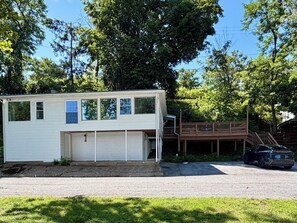 A single-story mobile home with a covered garage, a deck, and a car parked in front.