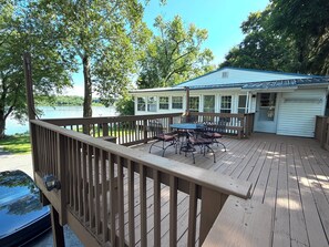 A deck with a table and chairs, overlooking a lake.