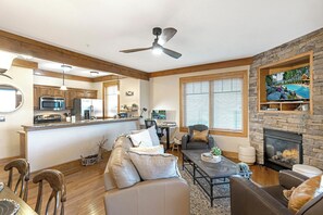 Una sala de estar moderna con chimenea, un comedor y una cocina con vigas de madera.