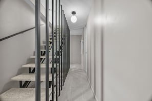 Een moderne trap met een metalen leuning, die uitkomt op een plateau met een lamp.