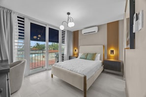 A hotel room with a bed, a desk, a chair, a balcony with a pool, and an air conditioning unit.