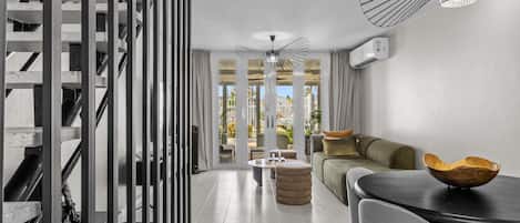 A modern living room with a sofa, a dining table, and a staircase.