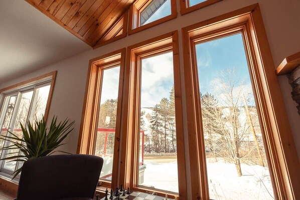 Una habitación con ventanas amplias, una silla y una planta.