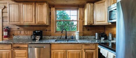 Una cocina con armarios de madera, lavavajillas de acero inoxidable, cafetera y microondas.