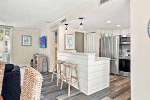 A compact kitchen with a central island, bar stools, and modern appliances. - MyStay at 3057 Seascape | South Forest Beach | Private Beach Cabana | Sleeps 7 (Hilton Head Island)