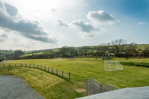 A grassy field with a soccer goal, a playground, and a wooden fence. - Large Converted Barn Near Abersoch | Gadlas-Sarn (Pwllheli)