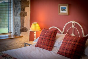 A bed with white bedding and red polka dot pillows, a bedside lamp, and a framed picture on the wall. - Large Converted Barn Near Abersoch | Gadlas-Sarn (Pwllheli)