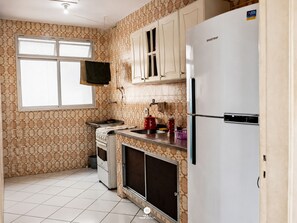 A kitchen with patterned wallpaper, a window, a stove, a refrigerator, and a sink. - Ap Cabo Frio a 5 min da Praia-Cabo Frio (Cabo Frio)