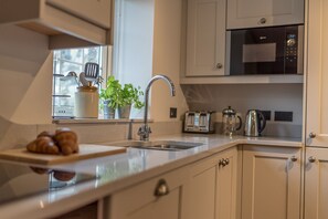 Eine moderne Küche mit Spüle aus Edelstahl, einem Toaster, einem Wasserkocher und einer Mikrowelle.