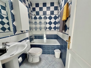 A bathroom with a bathtub, toilet, and sink.