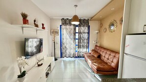 Eine moderne Küche mit Flachbildfernseher, braunem Ledersofa und Kühlschrank.