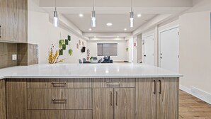 Una cocina moderna con una isla grande, armarios de madera e iluminación colgante.