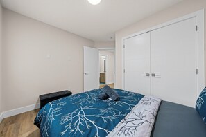 A bedroom with a bed, a wardrobe, and a small bedside table. - 2BHK - Close to Downtown/Whyte Ave/UOFA (Edmonton)