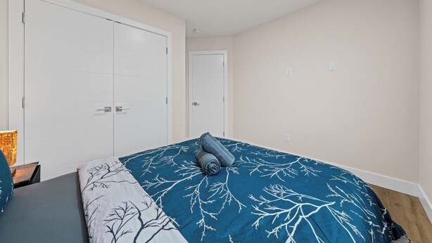 Un dormitorio con una cama, dos puertas y una mesita de noche con lámpara.