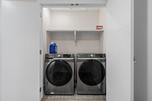 A laundry room with two front-loading washing machines and a shelf above them. - 2BHK - Close to Downtown/Whyte Ave/UOFA (Edmonton)