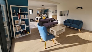 En moderne stue med en blå sofa, et hvidt sofabord og en reol.