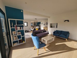 Ein modernes Wohnzimmer mit einem blauen Sofa, einem weißen Couchtisch und einem Bücherregal.