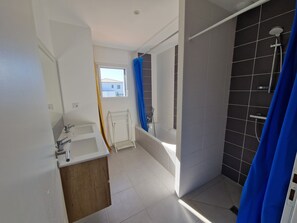 Ein Badezimmer mit einer Badewanne, einer Dusche und einem Fenster.