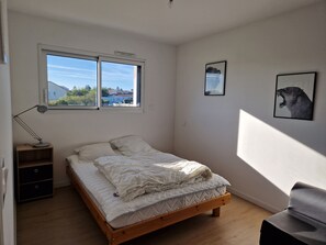 Ein Schlafzimmer mit Bett, Fenster, Schreibtisch und Stuhl.