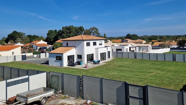 Et boligområde med moderne huse, en indhegnet gårdhave og en klarblå himmel.