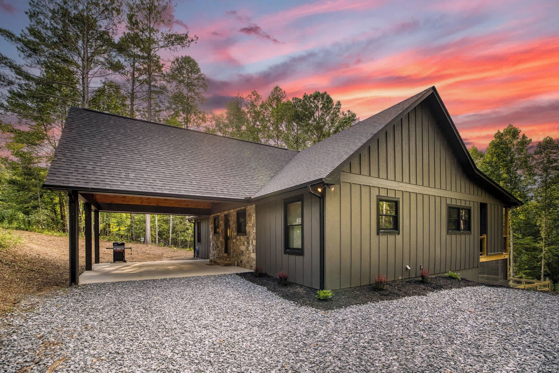 A two-story house with a covered porch and a gravel driveway.