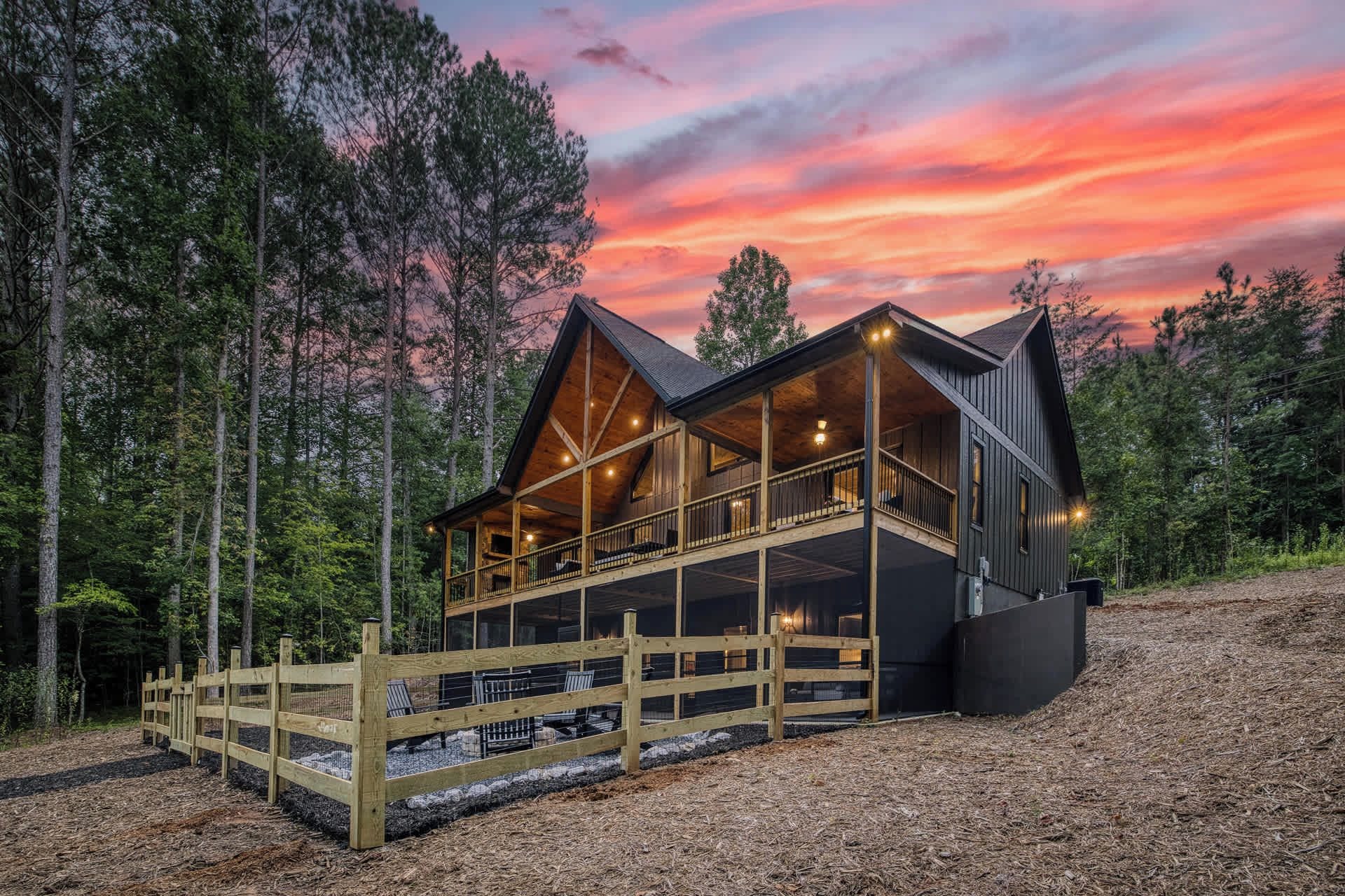 Een chalet met een houten terras en meerdere ramen, omringd door bomen.
